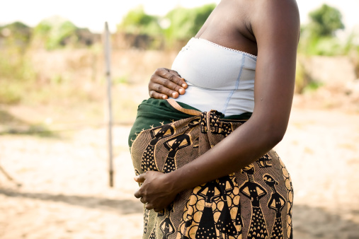 A pregnant African woman holding her stomach.